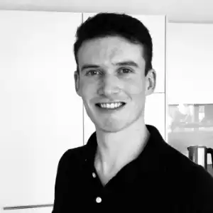 Schwarzweiss-Porträt Ihres IT-Supporters, lachend im schwarzem Poloshirt.